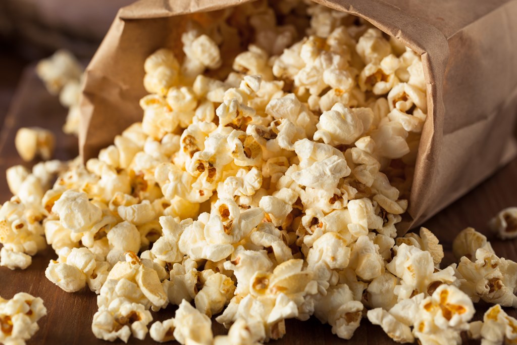 Homemade popcorn spilling from a brown paper bag.