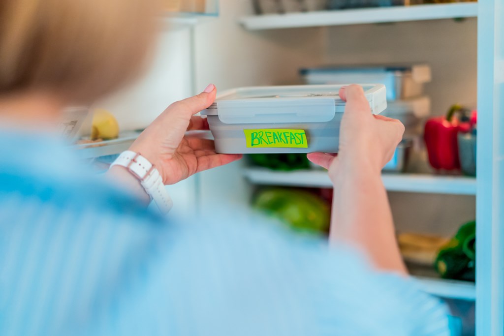 Woman putting prepared meal in the refrigerator.