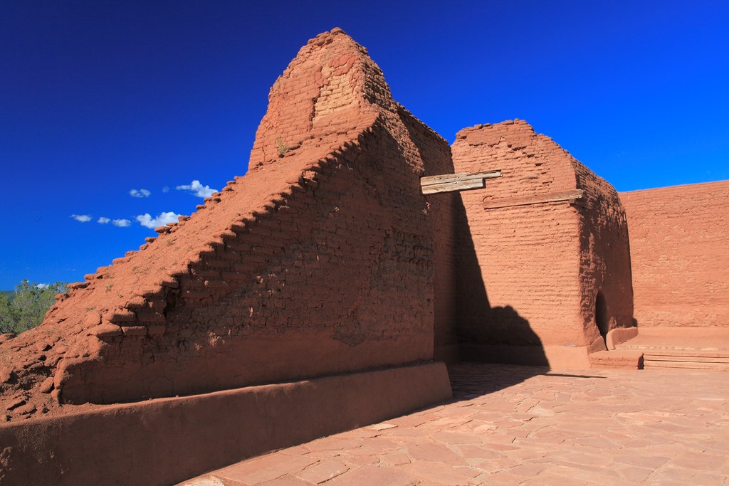 Red brick ruins in Pecos National Historical Park against a blue sky.