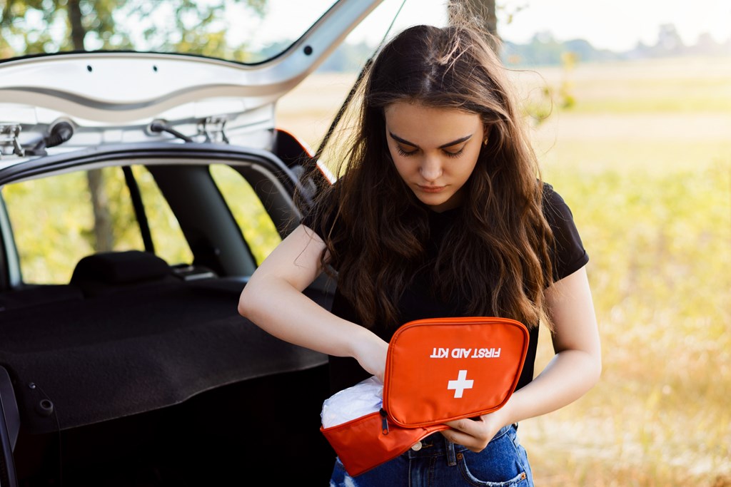 Young woman looking in a first aid kit near the back of an suv.