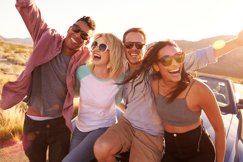 Friends stop for a photo on the side of a road during a road trip.