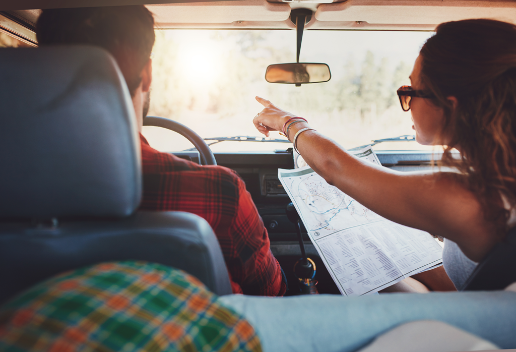 A young couple navigates a road trip using a paper map.