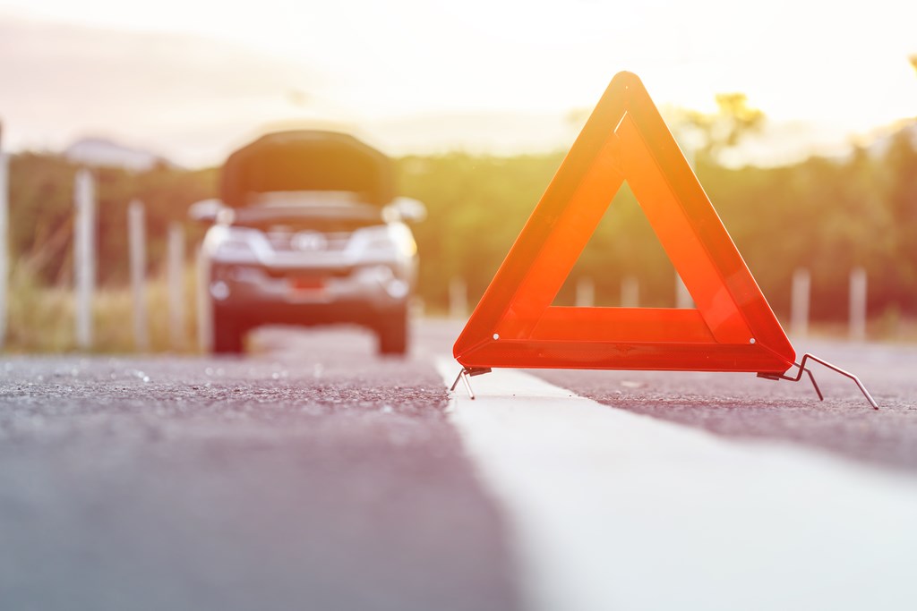 Red emergency stop sign and broken silver SUV car on the road