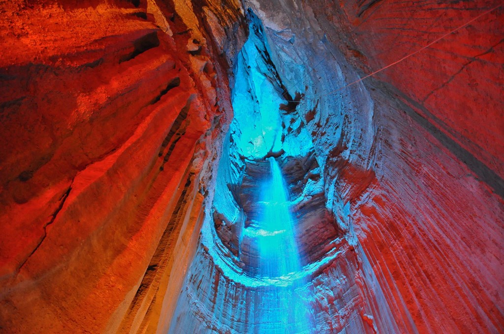 A waterfall inside a cave lit with blue lights.