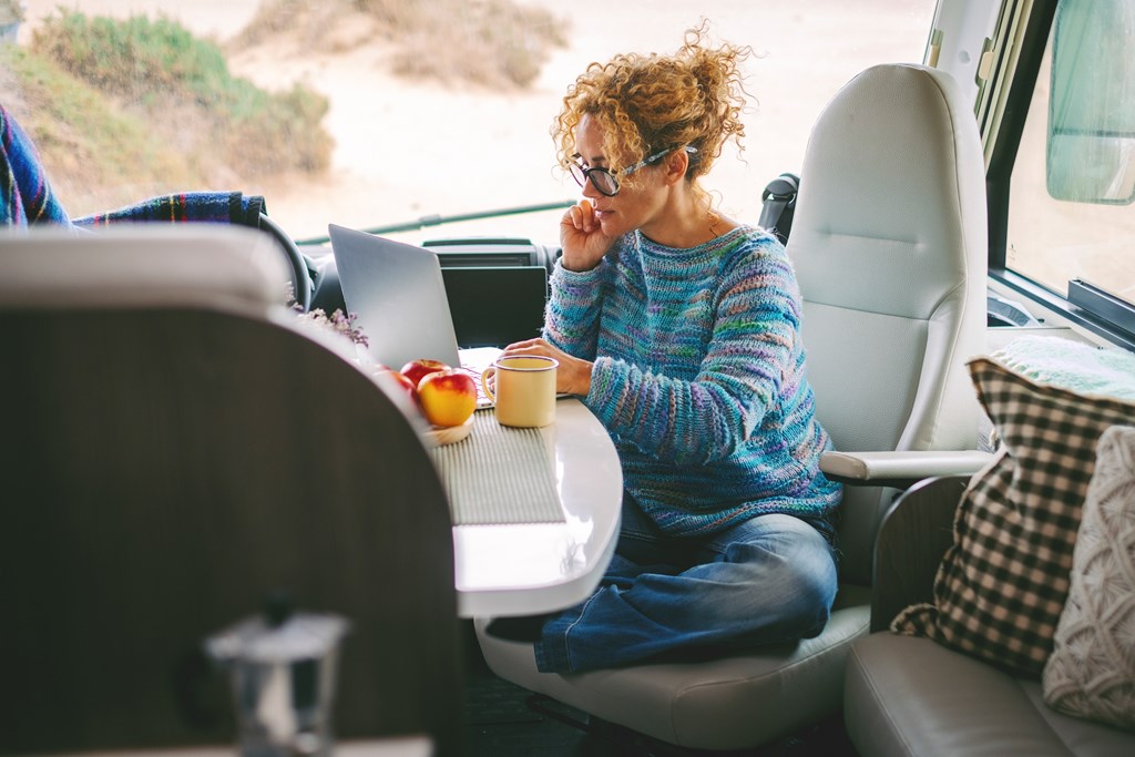 Woman working at a laptop inside her RV.