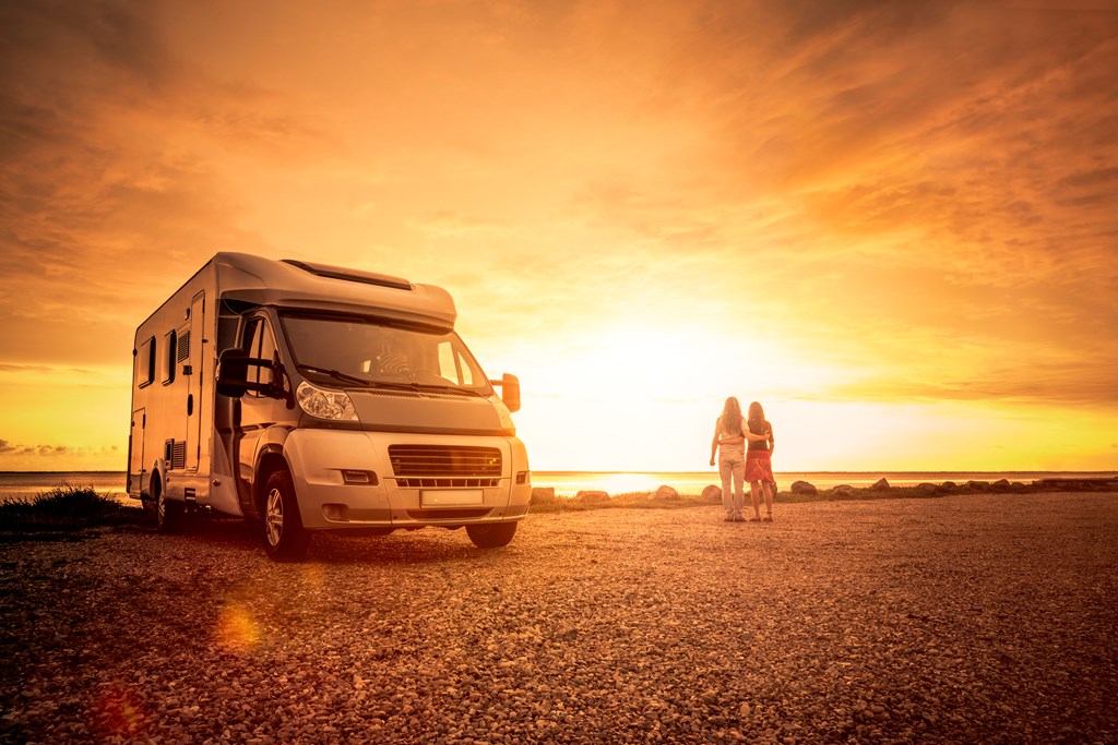 A couple watches the sunset by their RV.