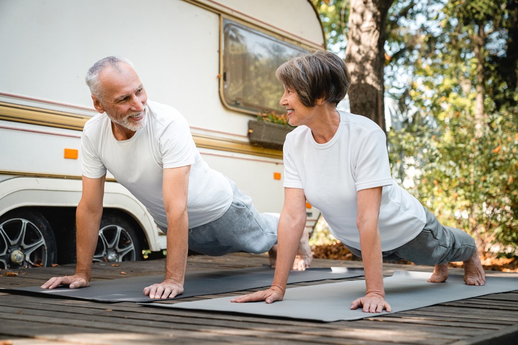 Active senior couple doing stretching exercises together outside an RV.