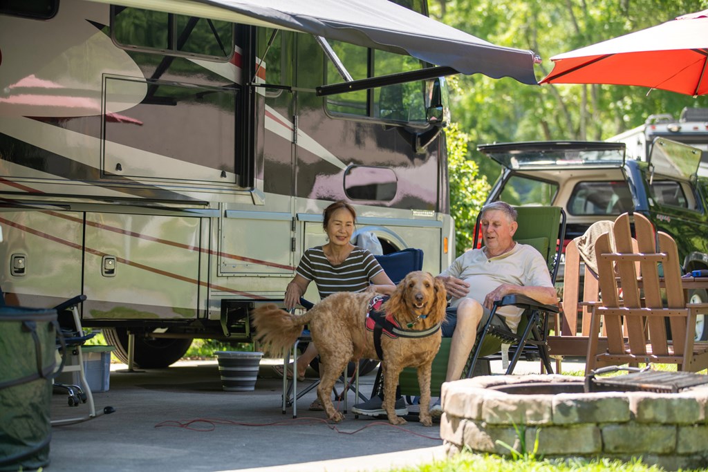 An older couple relaxes with their dog at a KOA campsite.