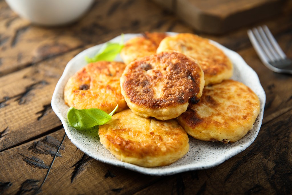 Homemade savory potato pancakes with fresh basil on a rustic background.