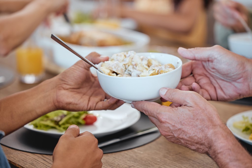 Closeup of family passing potato salad at the table.