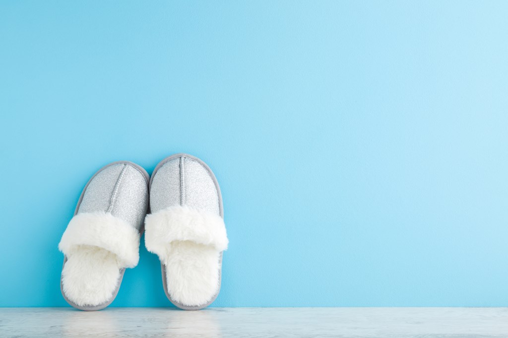 Gray slippers against a light blue wall.