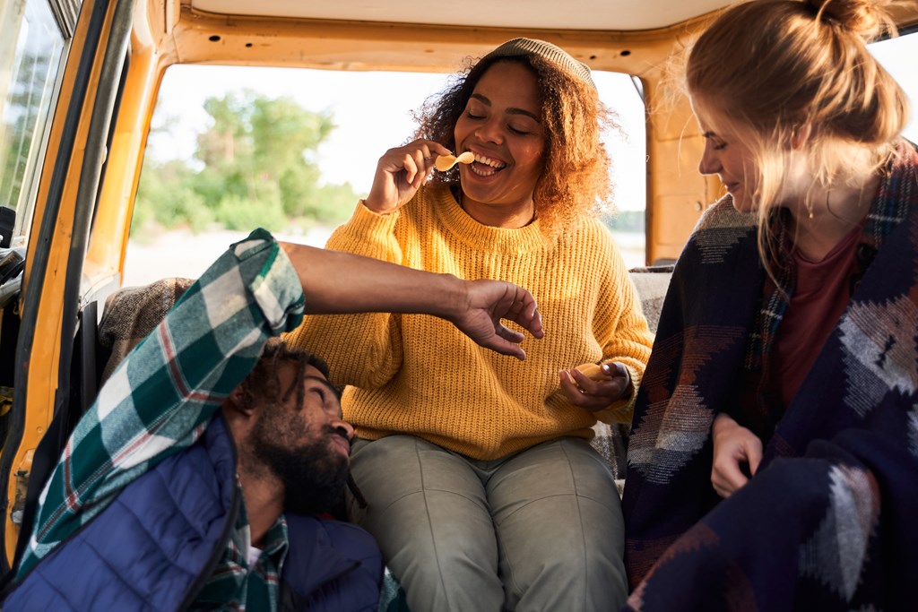 A group of friends on a road trip snack on chips.