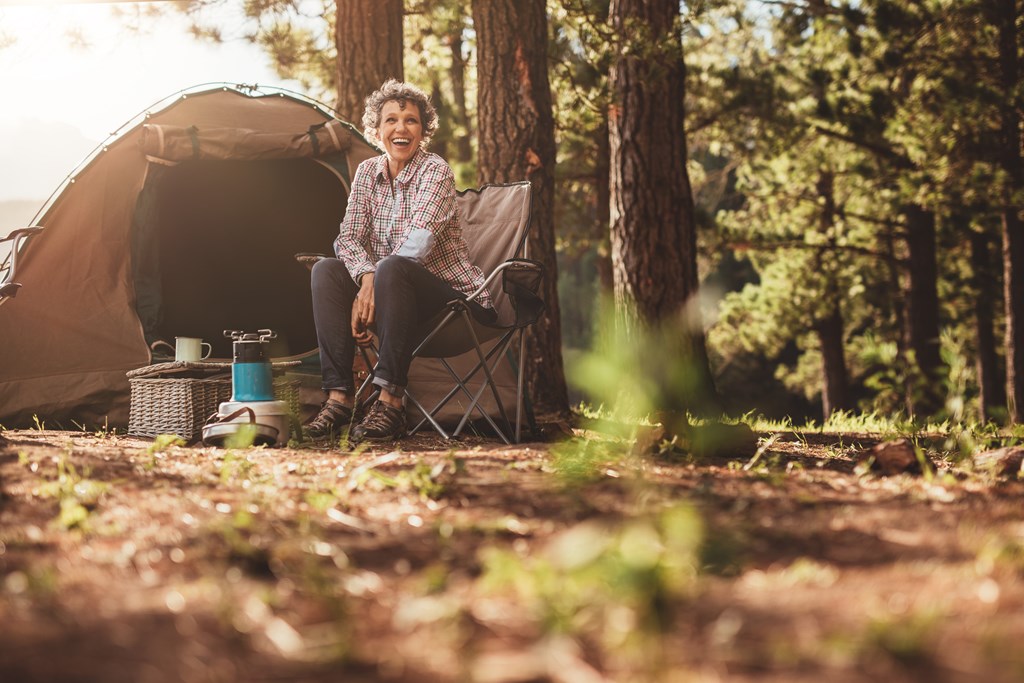 Woman sitting relaxed outside a tent.