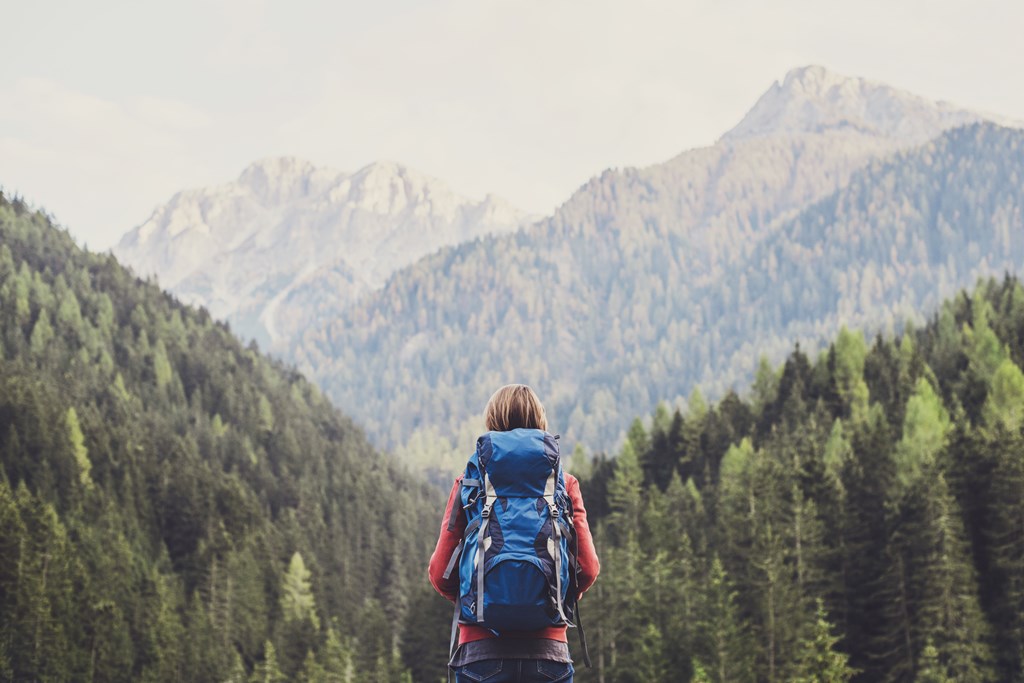 A young female solo hiker looks out onto the mountains.