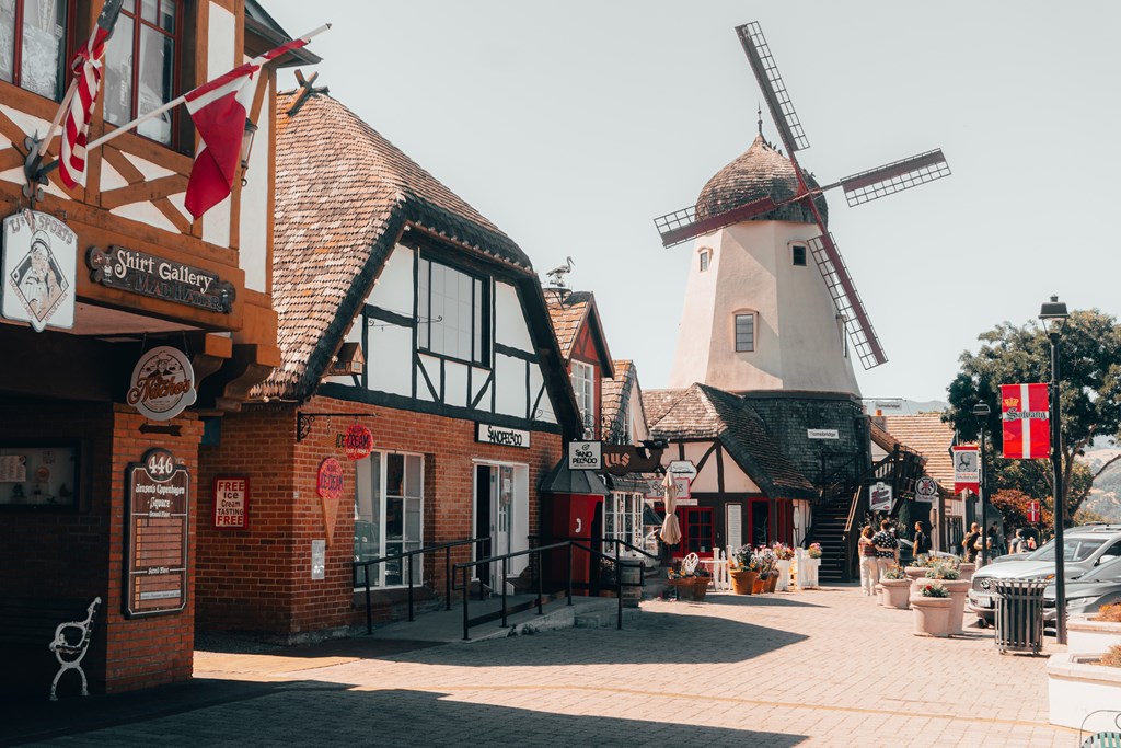 A street view in the European-themed town of Solvang, California. A windmill is pictured at the right of the cobblestone street.