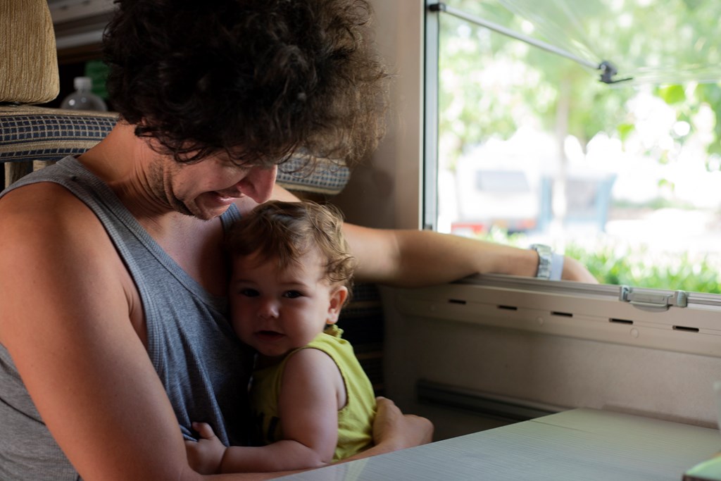 Father hugs his infant son in his RV.