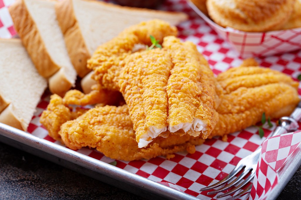 Southern fried fish with toast on a metal platter with red and white check paper.