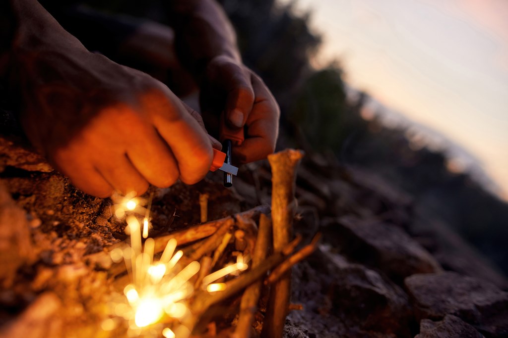 Close up of male hands making a fire with flint and steel in the wild. 