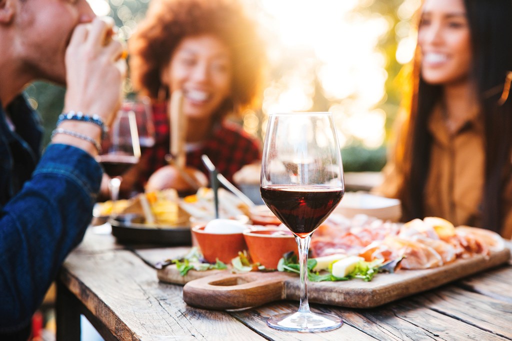 Happy family having barbecue party in backyard - Young friends celebrating at dinner drinking red wine at sunset - Focus on wine glass.