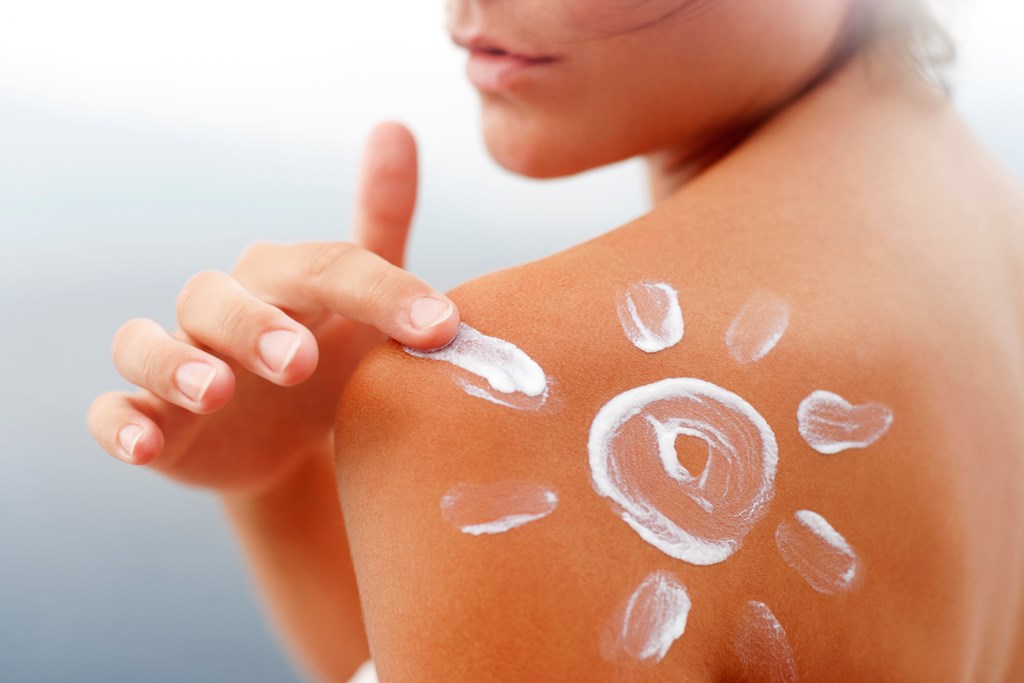 Woman's shoulder with sunscreen  lotion in shape of sun.