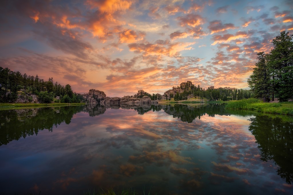 Stunning multicolored sunrise reflecting on Sylvan Lake in Custer State Park, SD.