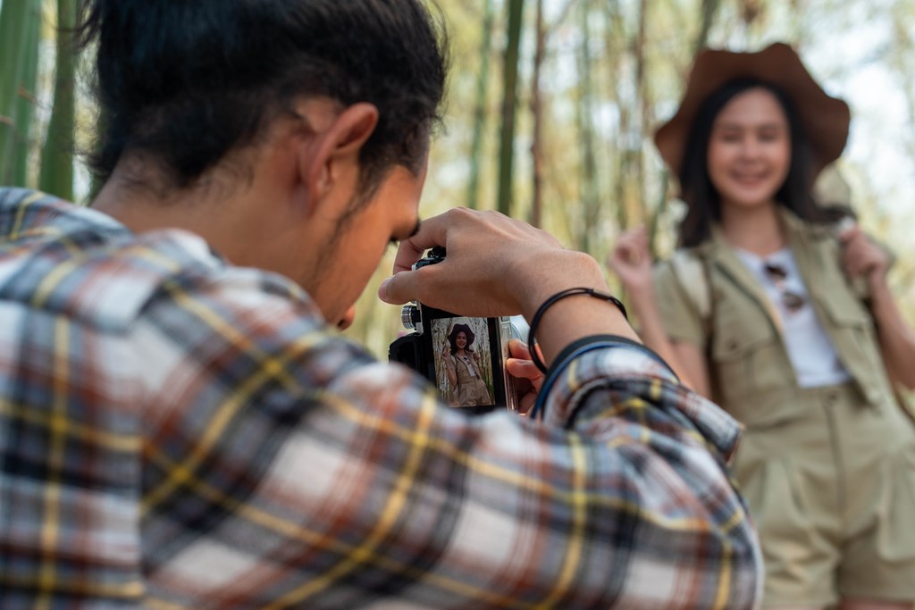 Young man taking a photo of his female traveling companion in the great outdoors.