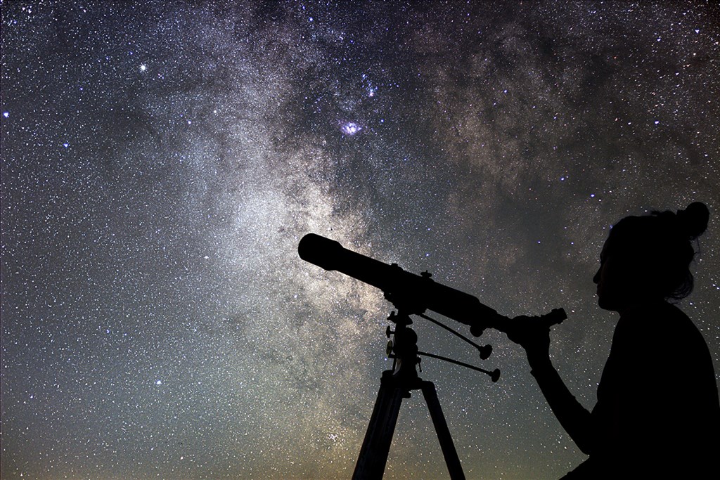 Woman watching the stars with a telescope.
