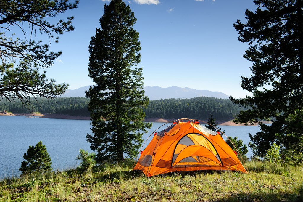 Small orange tent by a mountain lake