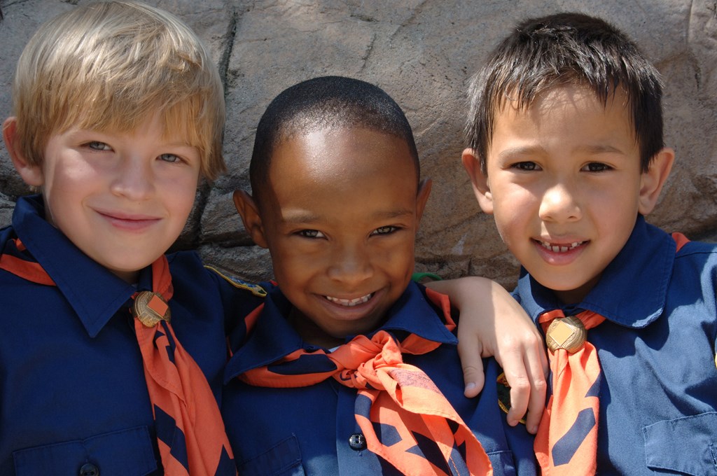 Three boys of diverse ethnic background in cub scout uniforms.