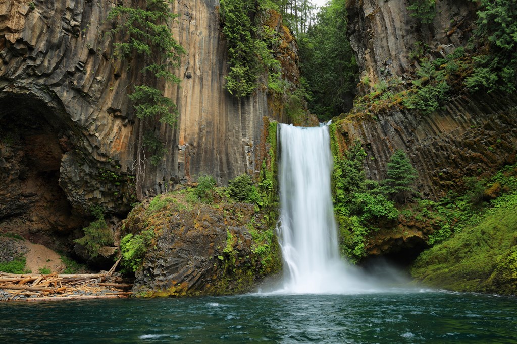 Toketee Falls, North Umpqua River, Oregon is a large waterfall surrounded by lush cliffs.