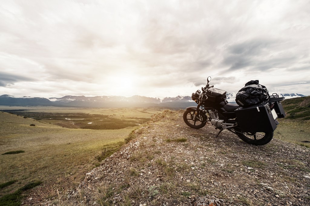 Motorcycle with trunks and bags overlooking a valley.