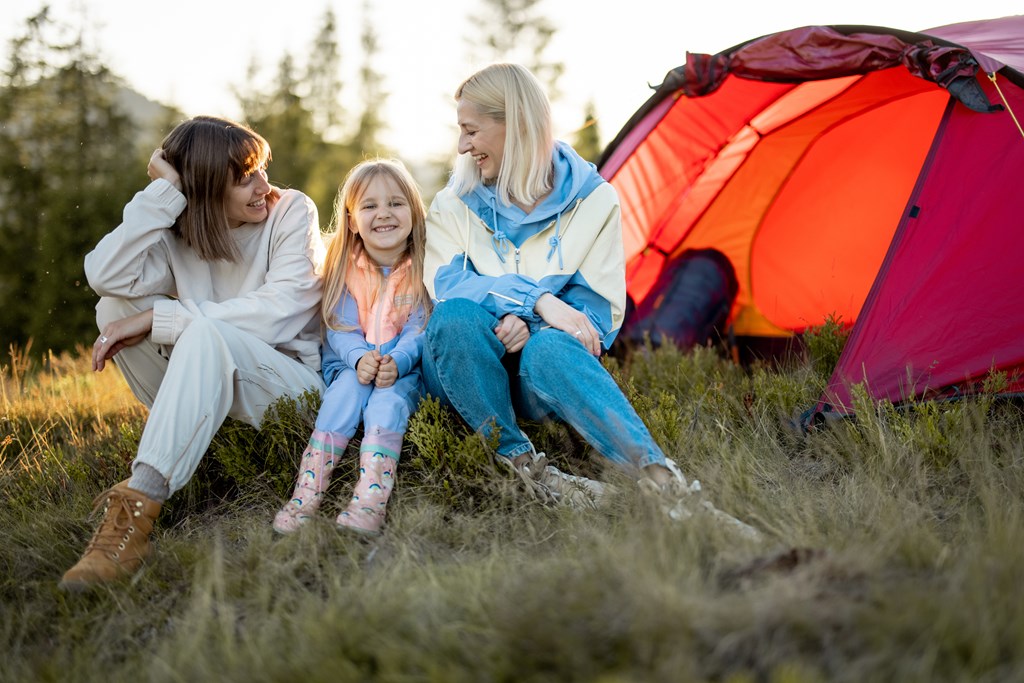 Two women camping with their little girl.