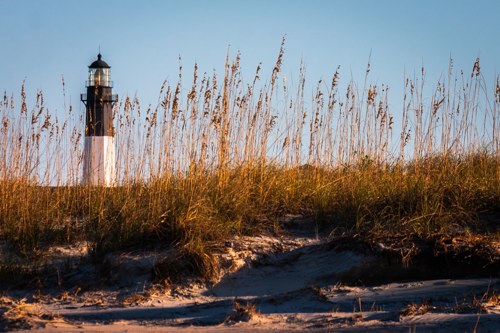 Tybee Island Lighthouse behind ocean grasses on the Atlantic Ocean in Georgia at sunset.