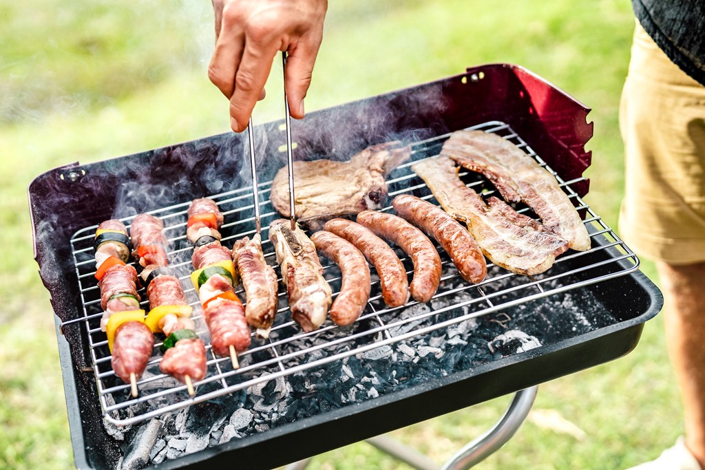 Closeup of a man grilling on a portable camping grill.