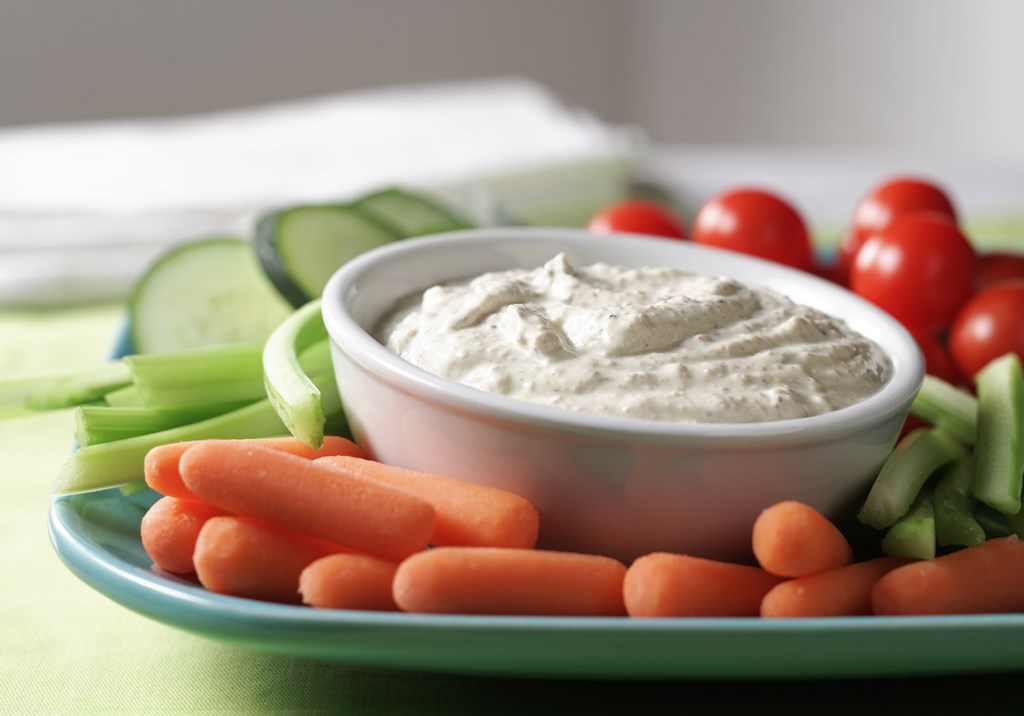 A close up of a mixed vegetable tray with creamy dip.