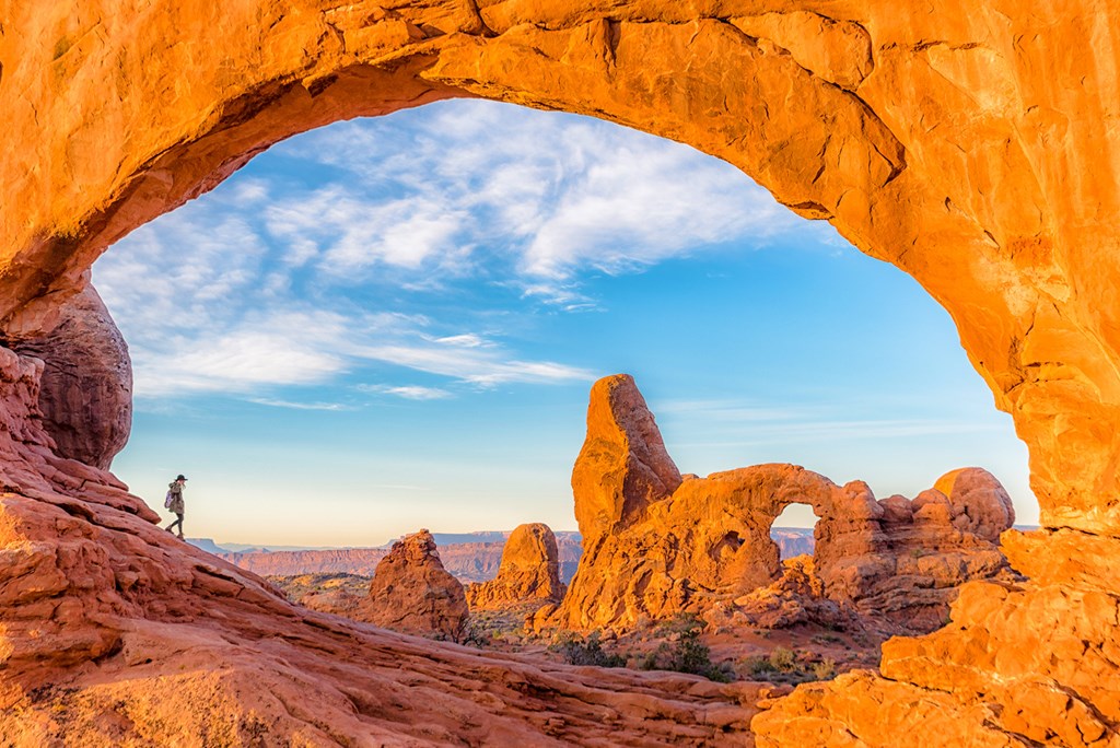 A woman walks through North Window Arch with Turret Arch in the background