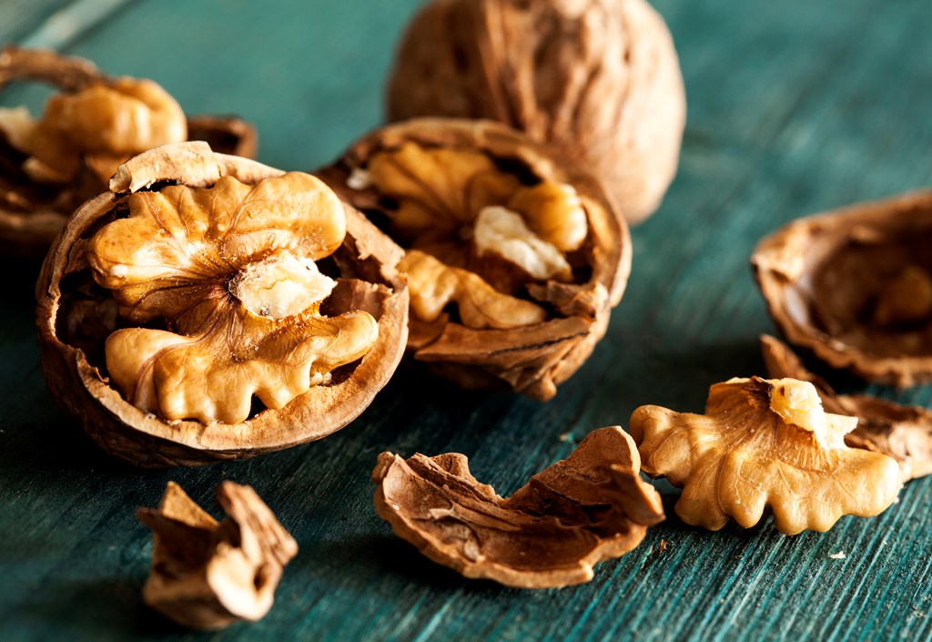 Cracked walnuts on a green wooden table.