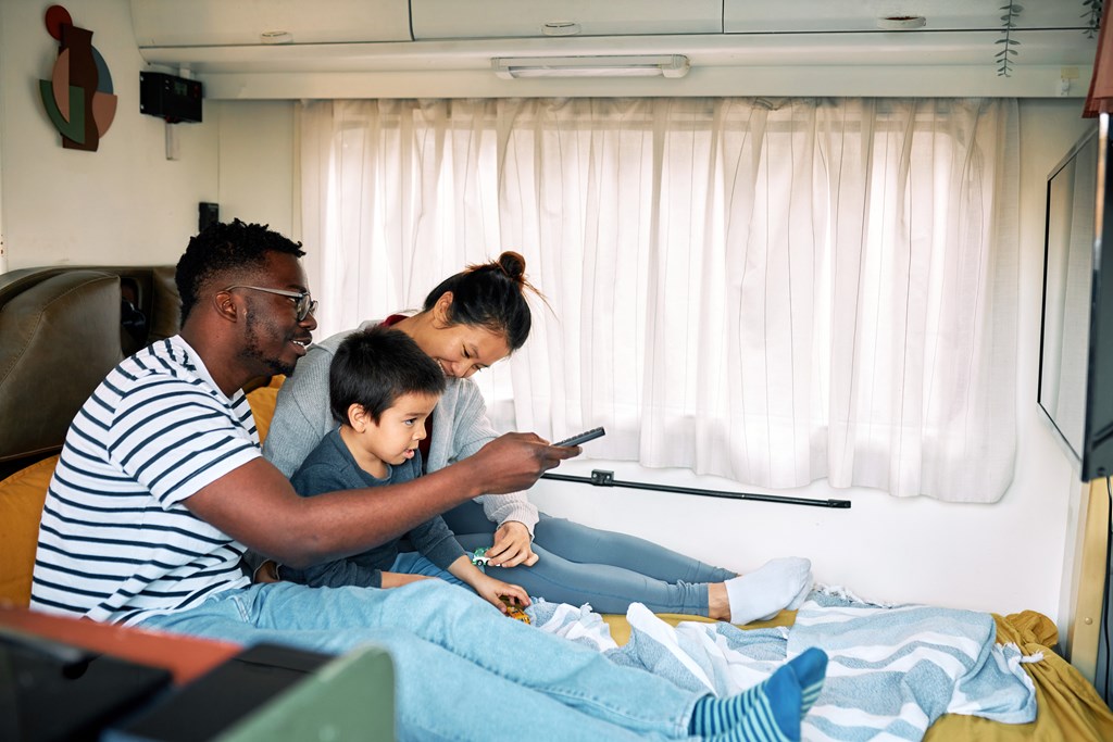 Young family of three with a son watch a movie in their RV.