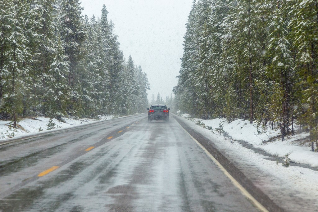 Car driving in snowfall in winter thru the Yellowstone national park , USA