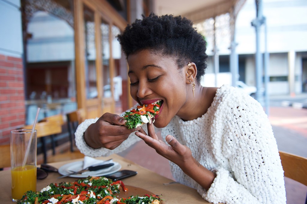 Woman eating a pizza on a restaurant patio.