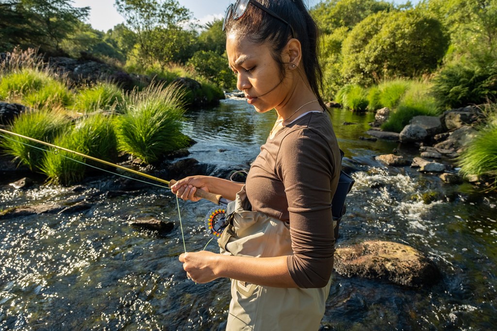 A young female standing fly fishing