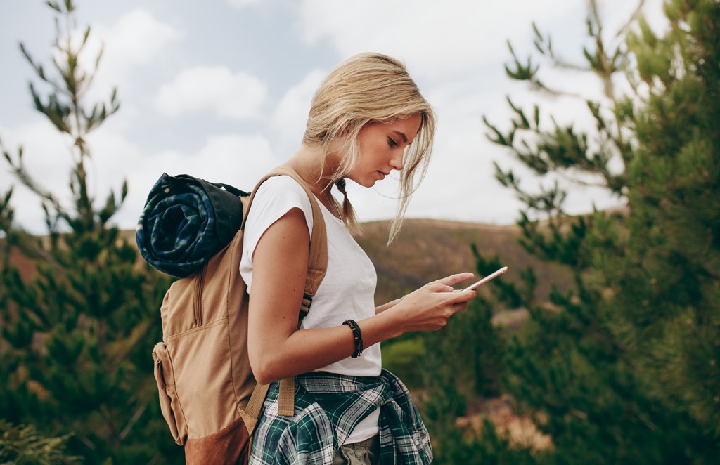Young woman on a hike using mobile phone for navigation.