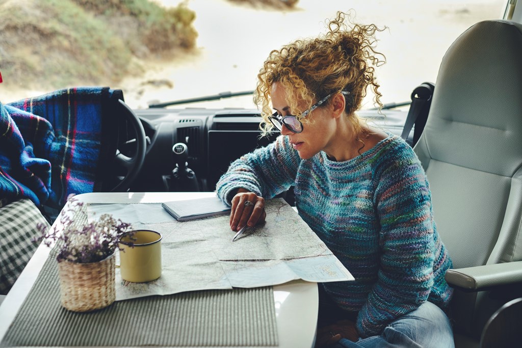 A solo female traveler looks at a map in her RV.