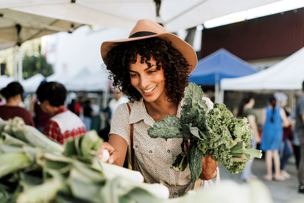 Woman buying kale at a farmers market.