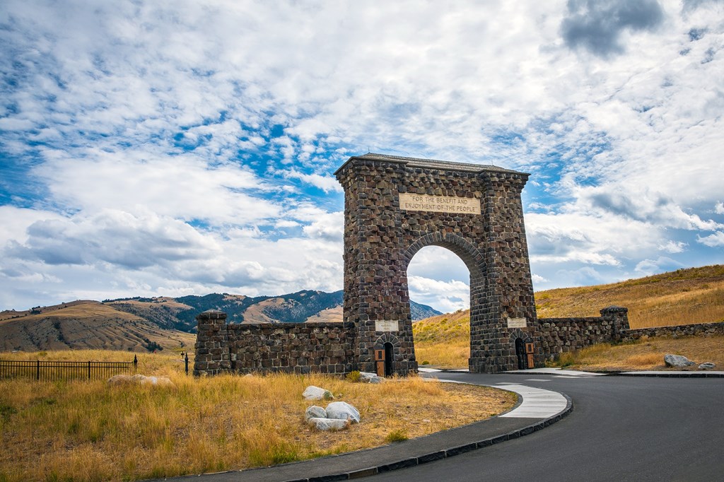 A grand view of the entrance/exit of Yellowstone National Park via the Roosevelt Arch. The day is ending and the clouds are rolling in on this historic landmark.