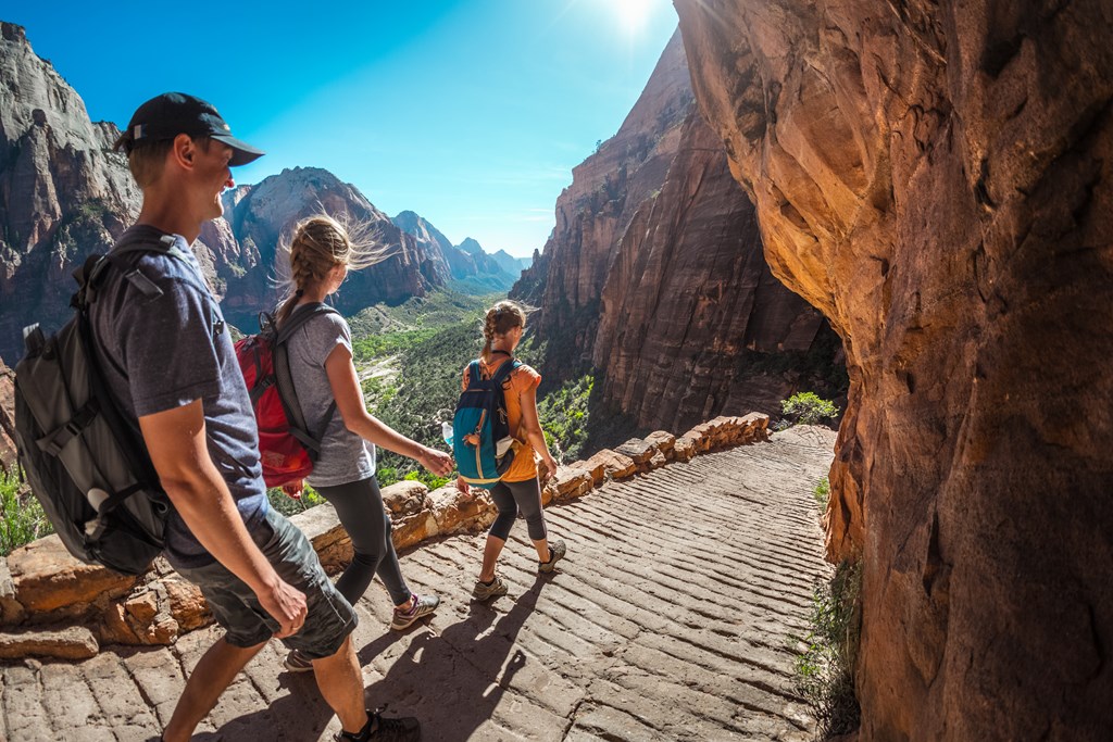 Group of hikers friends walking down the stairs and enjoying view of Zion National Park.