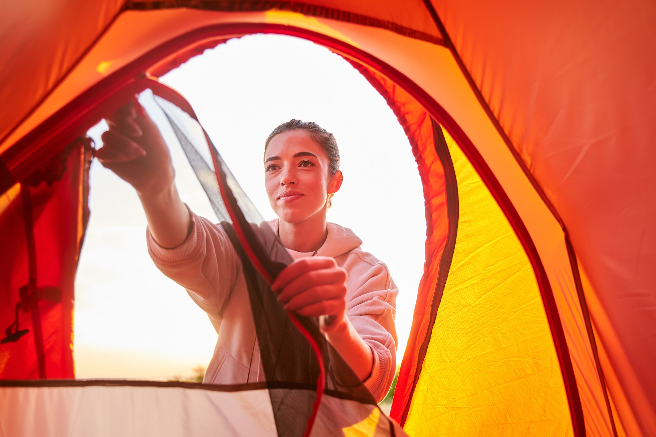 Young woman zipping the screen to her tent at a KOA campground.