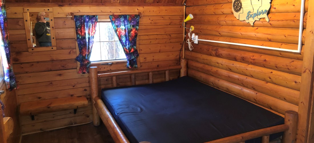 Front room of two room cabin with full size bed.
