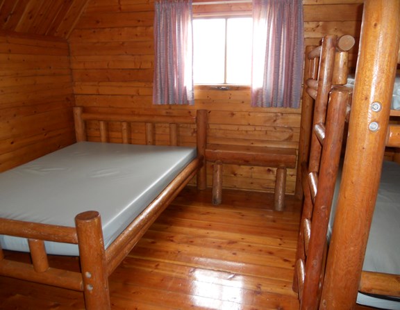 Camping cabins have air conditioning, heaters, screens, a small table and chair inside.  Outside, there is a porch swing, picnic table and fire ring.