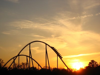 Closeup of a roller coaster at belmont park being illuminated by a bright orange sunset in the background.